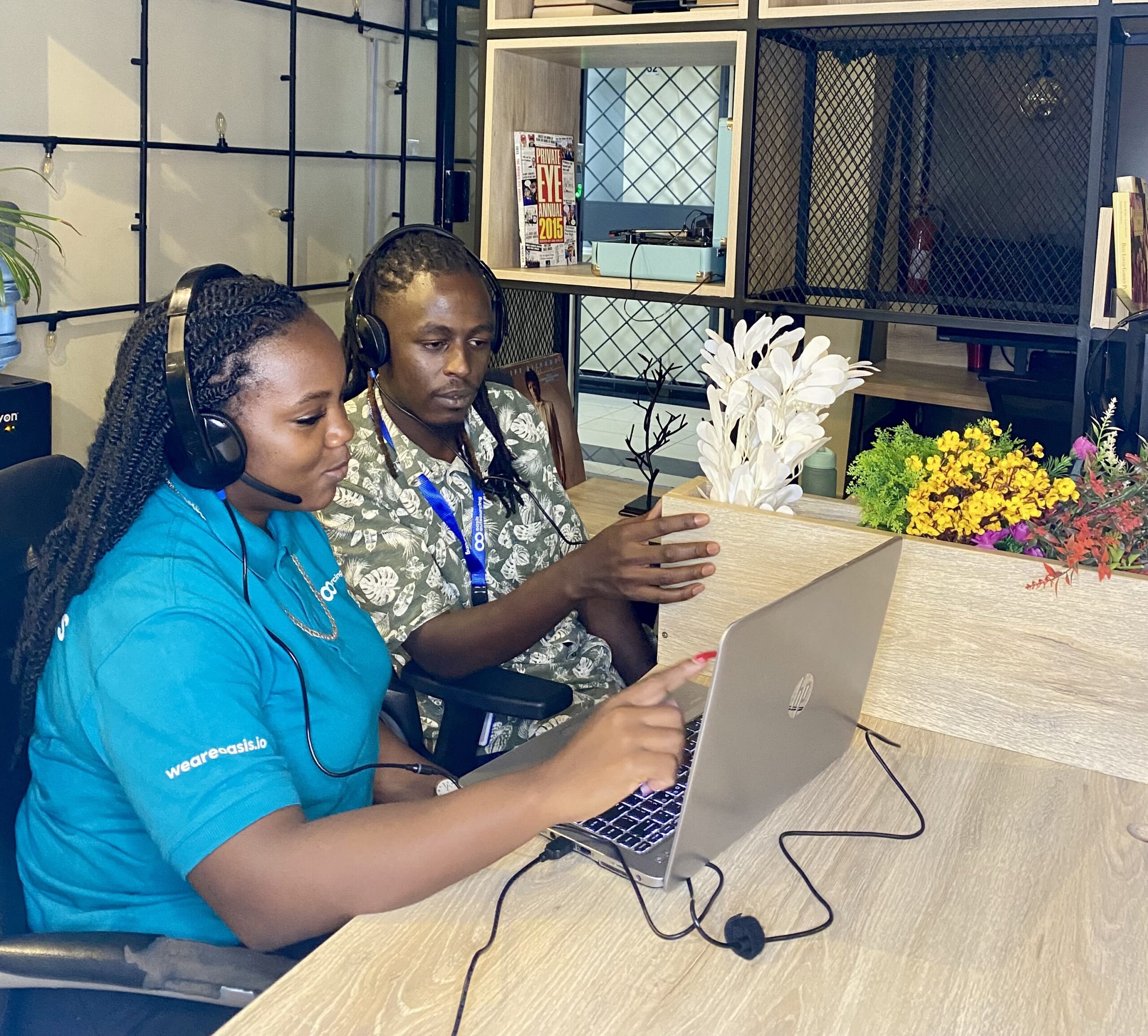 A customer support agent wearing a headset, conversing with a colleague at a desk in a collaborative workspace, highlighting the true value of BPO in fostering teamwork and delivering exceptional customer service